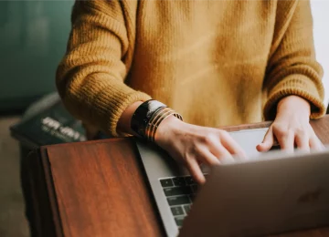 A woman typing on a laptop, representing the online counselling and therapy services offered by Lynn Guthrie.